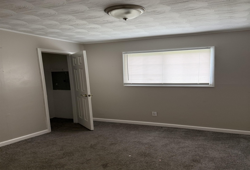 Room featuring neutral-toned walls, textured ceiling, a window with blinds, and wall-to-wall carpeting