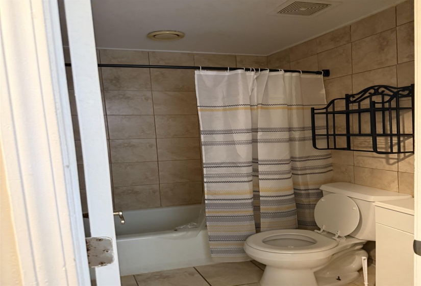 Bathroom featuring a built-in tub with tile surround, a toilet, and a vanity cabinet