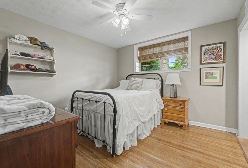 Bedroom featuring wood-finish flooring, a window with natural light, and a ceiling fan with light fixture