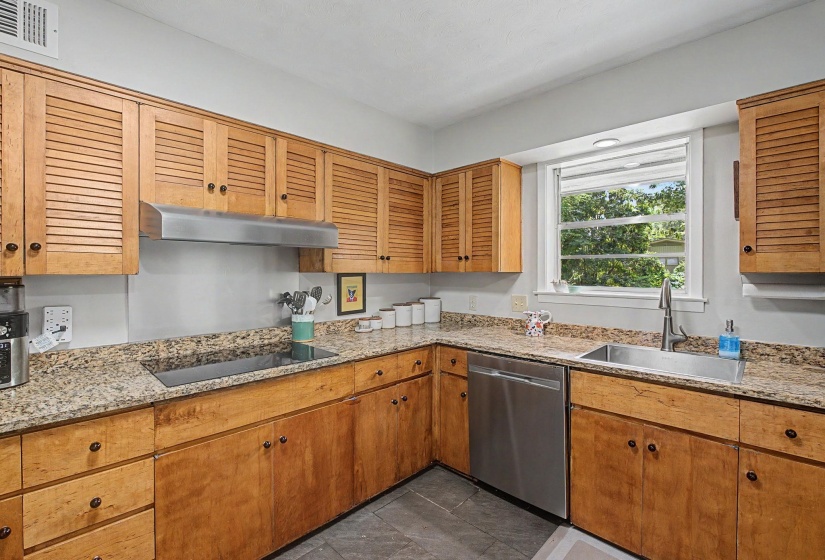 Kitchen featuring wood cabinetry, granite-finish countertops, stainless steel appliances, and a window with natural light
