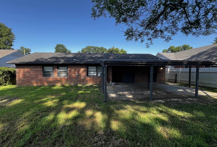 Rear view of property with a patio, brick siding, and an attached carport