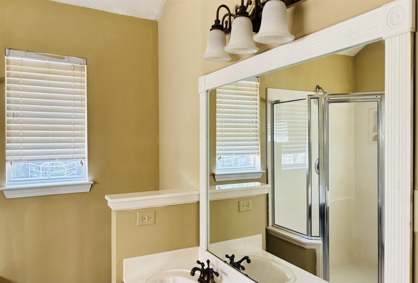 Bathroom vanity with dual sinks, a large framed mirror, and a three-light fixture