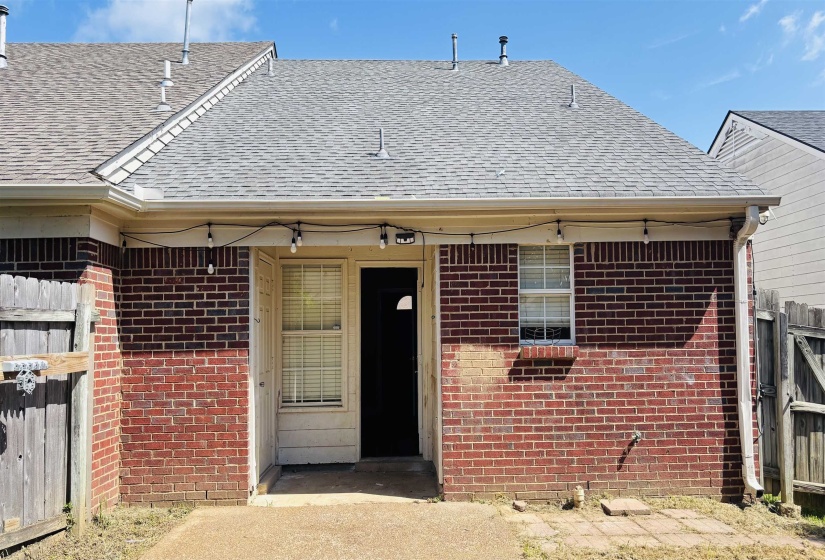 Brick exterior featuring a private patio, white-framed windows, and a shingled roof