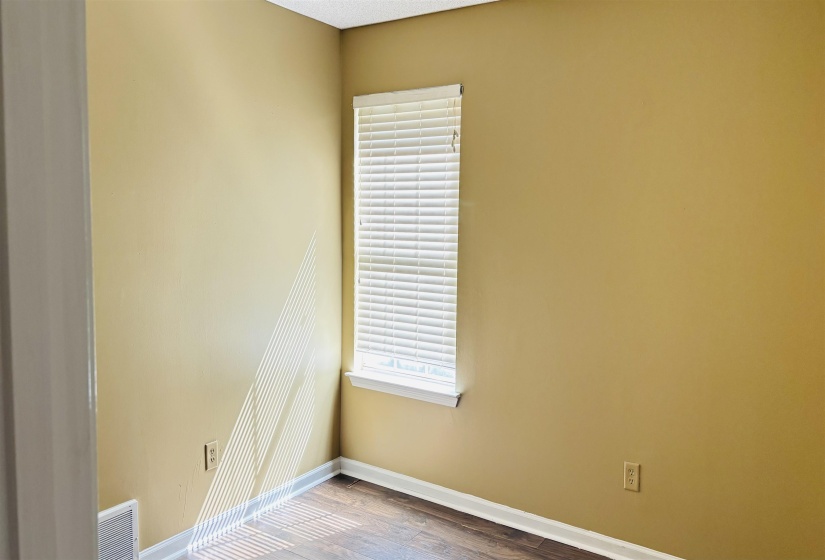 Room featuring wood-finish flooring, a neutral wall color, and a window with horizontal blinds