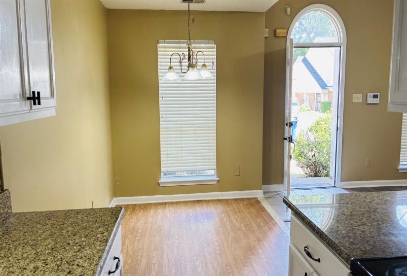 Dining area featuring a decorative chandelier and a large window with horizontal blinds