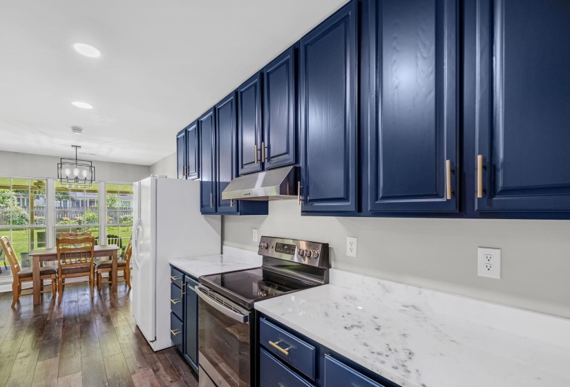 Kitchen featuring blue cabinetry with gold-tone hardware, white marble-look countertops, and stainless steel appliances