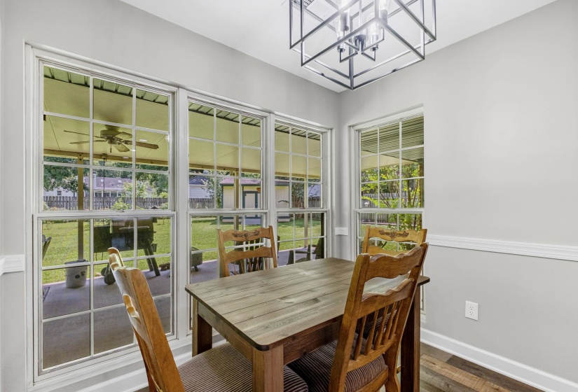 Dining area featuring multiple large windows with muntins, a contemporary ceiling light fixture, light gray wall paint, and wood-finish flooring