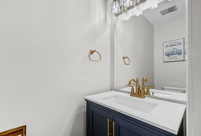 Vanity featuring a white countertop with an integrated sink, a dark blue base cabinet, and gold-finish fixtures