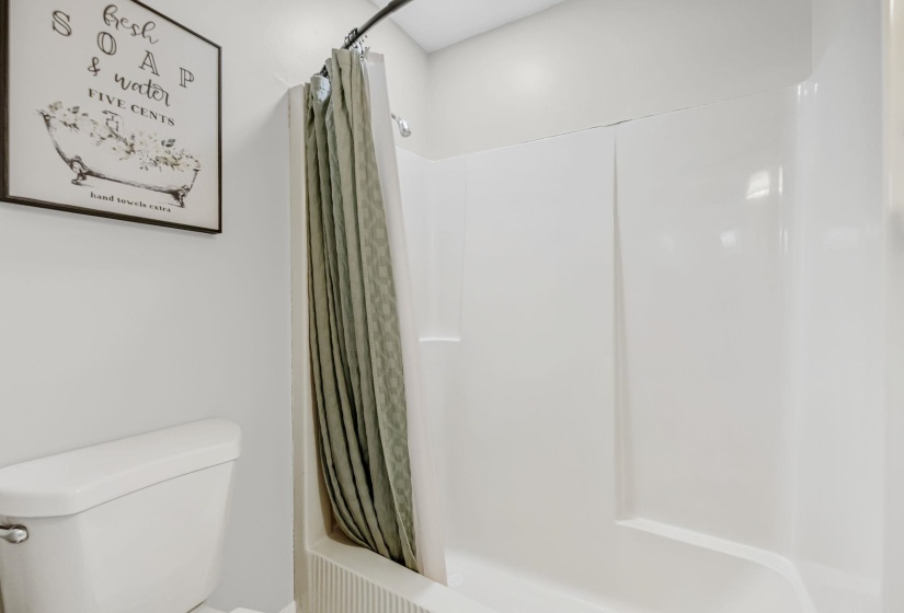 White acrylic tub and shower combination with a curved shower curtain rod
