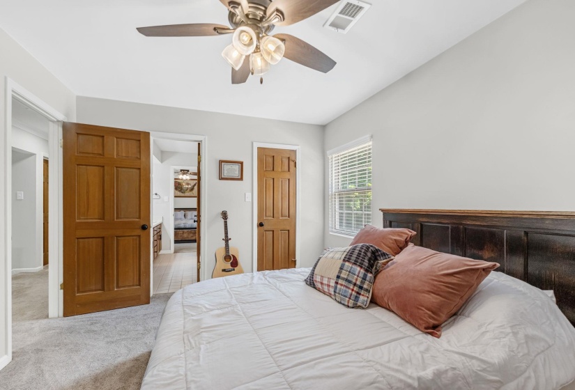 Carpeted room with a ceiling fan, a window with blinds, and two wood-paneled doors