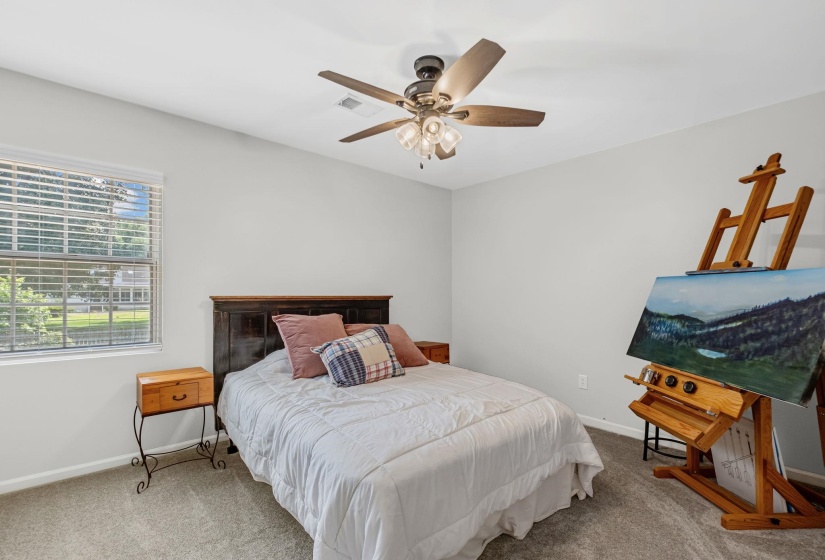 Neutral wall paint with textured carpeting, a ceiling fan with light fixture, and a window featuring horizontal blinds