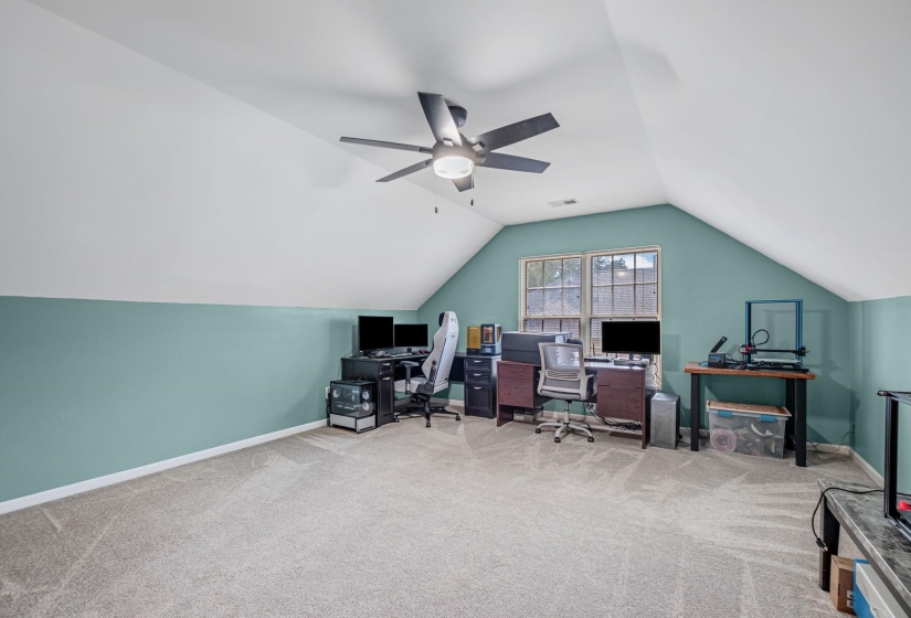 Spacious room with sloped ceilings and a ceiling fan