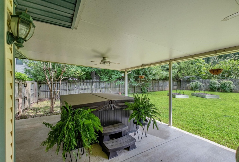 Covered patio featuring a ceiling fan, exterior lighting, and a hot tub