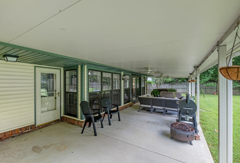 Expansive covered patio featuring a concrete surface, white vinyl siding, a painted ceiling, and multiple ceiling fans