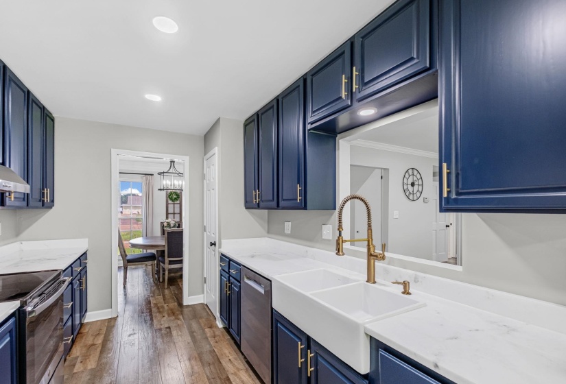 Kitchen featuring navy blue cabinetry with gold-tone hardware, white countertops, and wood-finish flooring