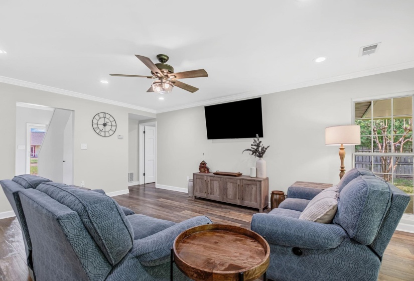 Spacious living area featuring wood-finish flooring, recessed lighting, and a ceiling fan with light fixture