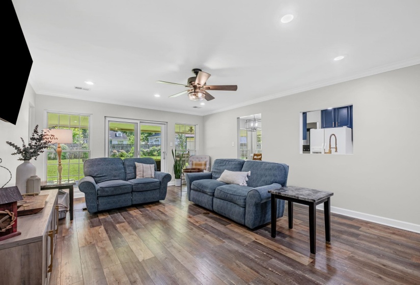 Expansive living area featuring rich wood-finish flooring and ample natural light from multiple windows and a sliding glass door