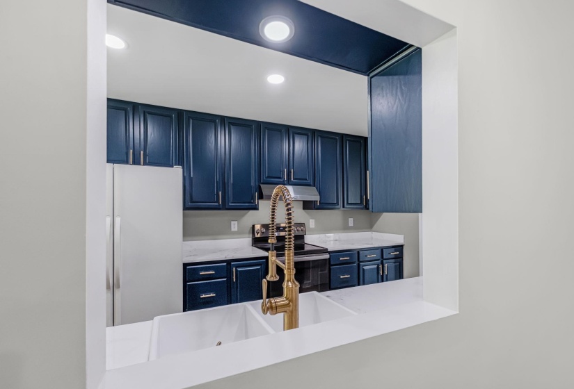Kitchen pass-through featuring dual white undermount sinks with a gold-tone gooseneck faucet
