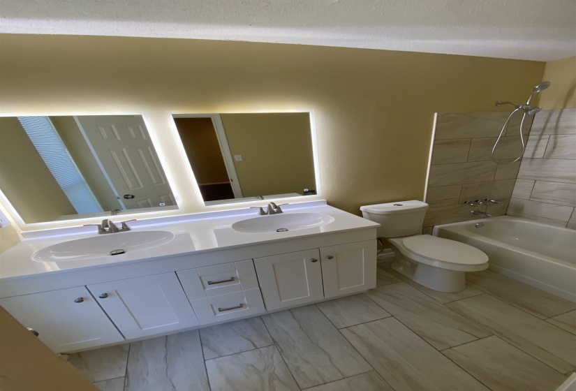 Bathroom featuring a dual vanity with white cabinetry, light-colored countertops, and integrated vessel sinks