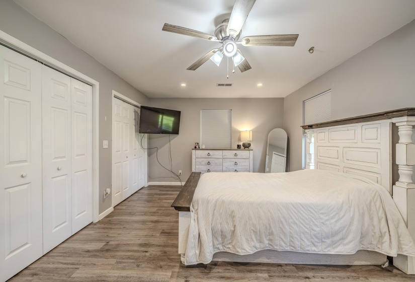 Spacious room featuring wood-finish flooring, two sets of bi-fold closet doors, a ceiling fan with integrated lighting, and recessed lighting