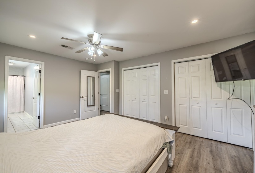 Spacious room featuring wood-finish flooring, light grey walls, and a ceiling fan with integrated lighting