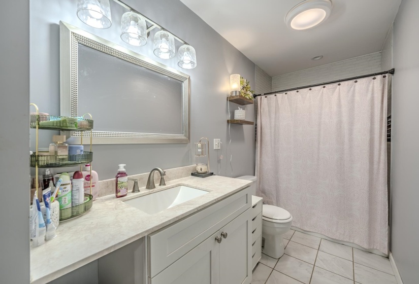 Bathroom featuring a single vanity with a white countertop, an undermount sink, and a brushed nickel faucet