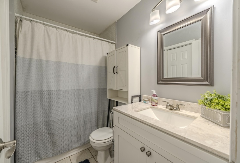 Bathroom featuring a single vanity with a solid surface countertop, an undermount sink, and a framed mirror