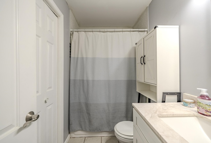 Bathroom featuring a built-in vanity with a light-toned countertop, a toilet, and a stand-alone storage cabinet