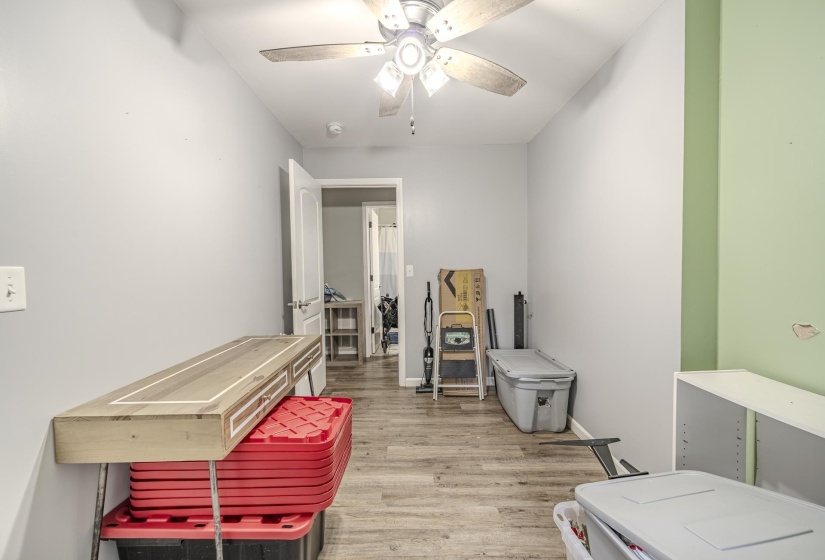 Interior room featuring wood-finish flooring, a ceiling fan with integrated lighting, and neutral wall tones