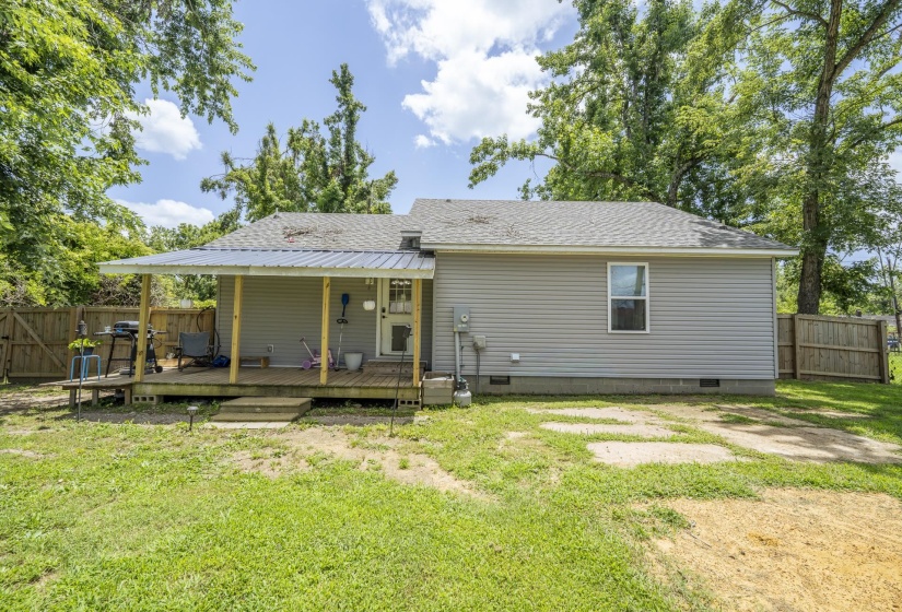 Rear exterior featuring a covered porch with a metal roof, wood deck, and three-step entry