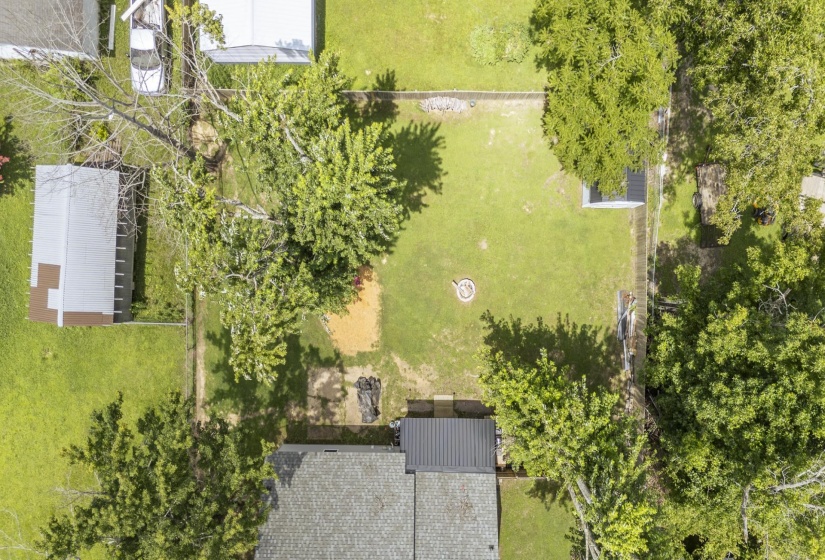 Expansive backyard featuring a manicured lawn, perimeter fencing, and mature trees
