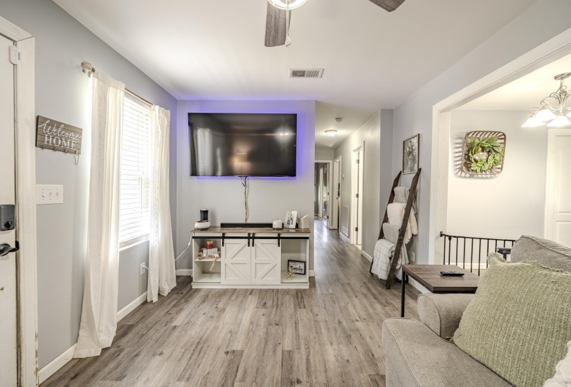 Spacious living area featuring wood-finish flooring, a ceiling fan, and ample natural light from the window