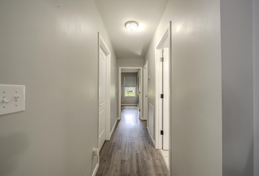 Hallway featuring wood-finish flooring, light gray wall paint, white trim, and recessed lighting