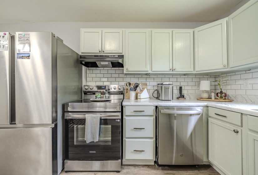 Kitchen featuring white shaker-style cabinetry, white subway tile backsplash, and light-toned countertops