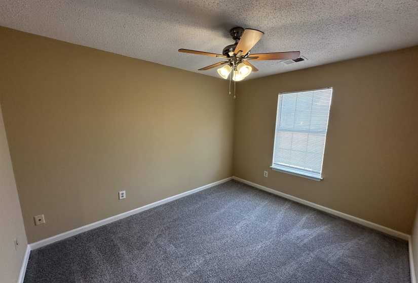 Carpeted room featuring a ceiling fan with integrated lighting, a double-hung window with blinds, and neutral wall paint