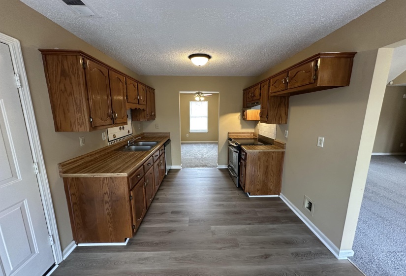 Kitchen featuring wood-finish flooring, wood cabinetry, laminate countertops, and stainless steel appliances
