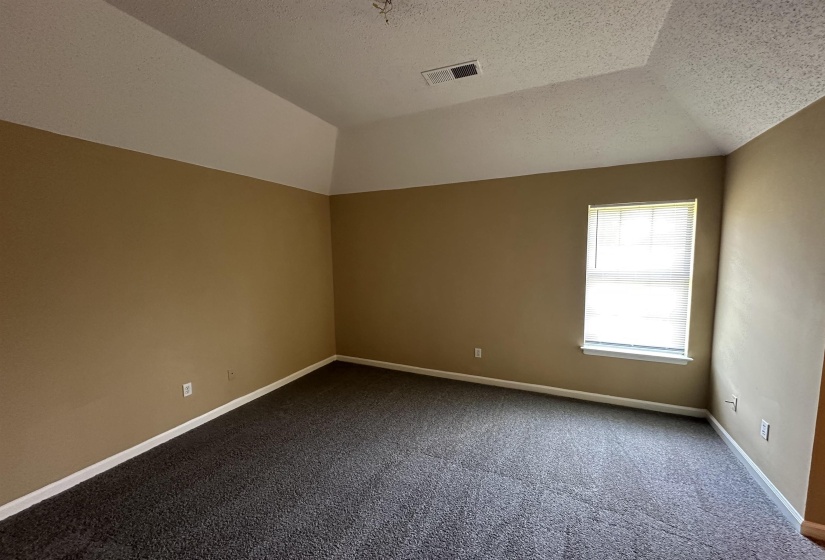 Spacious room featuring a tray ceiling, neutral wall tones, and dark carpeting
