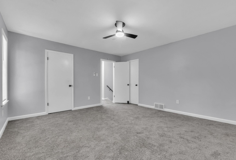 Carpeted room featuring light gray walls, white baseboards, and a ceiling fan with integrated lighting