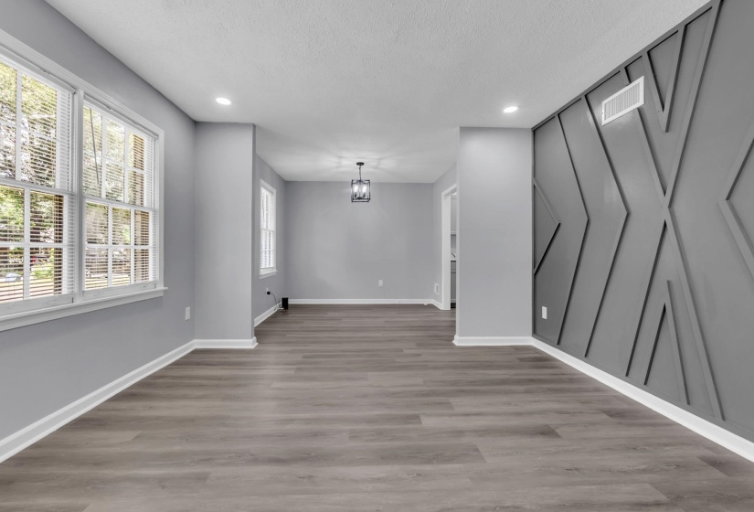 Spacious room featuring wood-finish flooring, recessed lighting, and a decorative accent wall