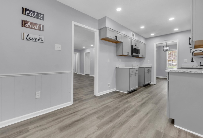 Modern kitchen featuring light gray cabinetry, wood-finish flooring, recessed lighting, a built-in microwave, and a dark-toned faucet