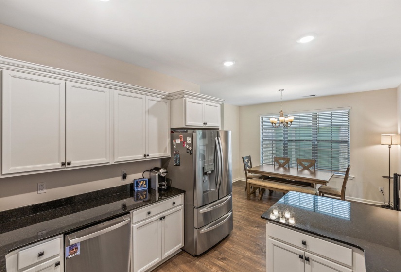 Kitchen featuring white cabinetry, dark stone countertops, stainless steel appliances, and wood-finish flooring