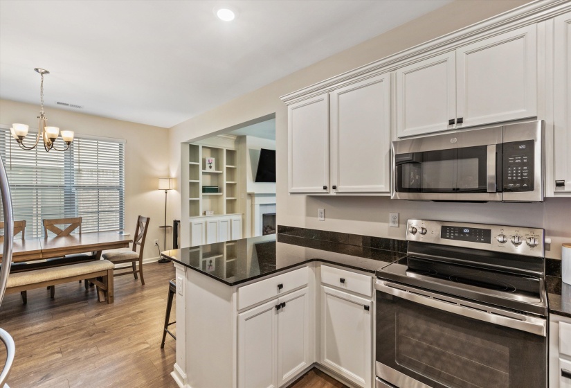 Kitchen featuring white cabinetry, dark countertops, stainless steel appliances, and wood-finish flooring