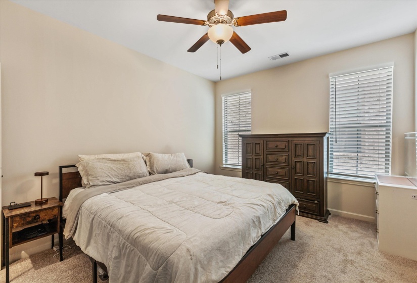 Carpeted room featuring a ceiling fan with integrated lighting, two windows with blinds, and light-toned walls