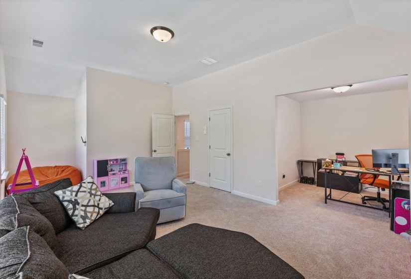 Carpeted open-concept bonus room featuring a recessed office nook with an overhead flush mount light fixture, and a separate windowed alcove