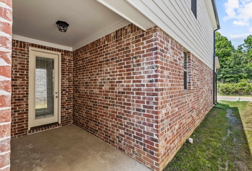 Brick exterior with white siding and a covered concrete patio