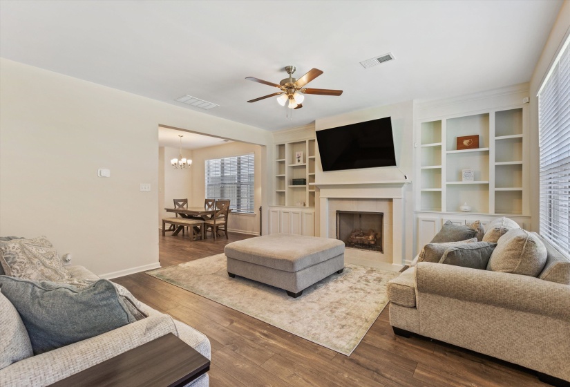 Living area featuring wood-finish flooring, a ceiling fan, and a fireplace with an integrated entertainment center