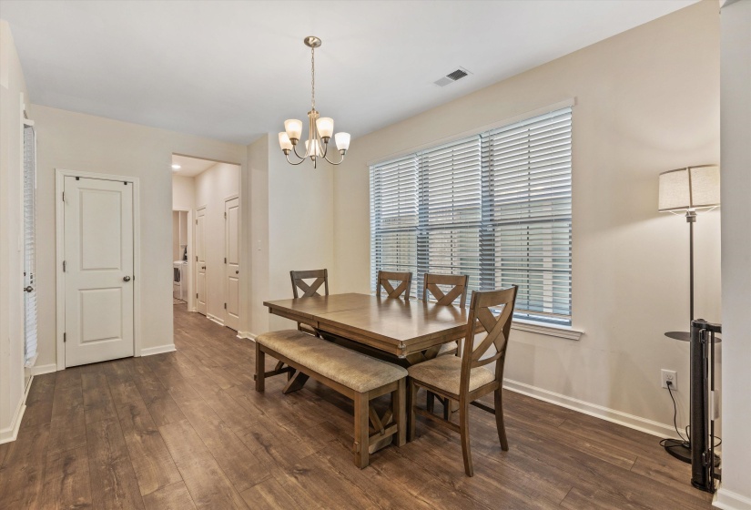 Dining area featuring wood-finish flooring, a window with horizontal blinds, and a multi-light chandelier