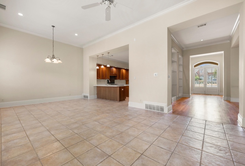 Spacious interior featuring tile flooring, crown molding, recessed lighting, a ceiling fan, and an open concept to the kitchen with wood-finish cabinetry