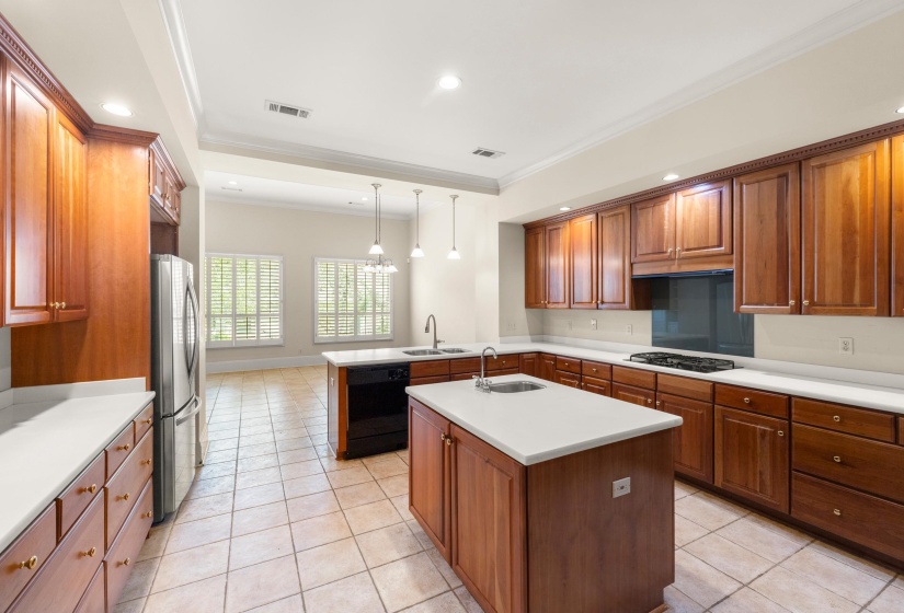 Spacious kitchen featuring two islands, extensive wood cabinetry, stainless steel appliances, and solid surface countertops