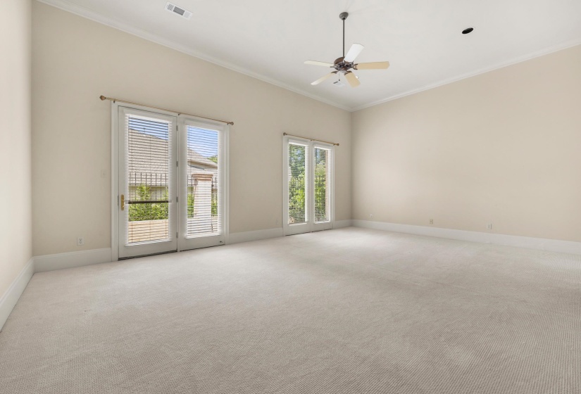Spacious room featuring vaulted ceilings, neutral-toned carpeting, and two sets of French doors providing exterior access